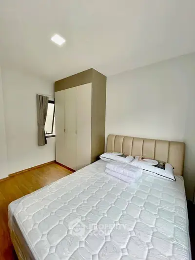 Cozy bedroom with modern design and ample natural light, featuring a comfortable bed and sleek wardrobe.