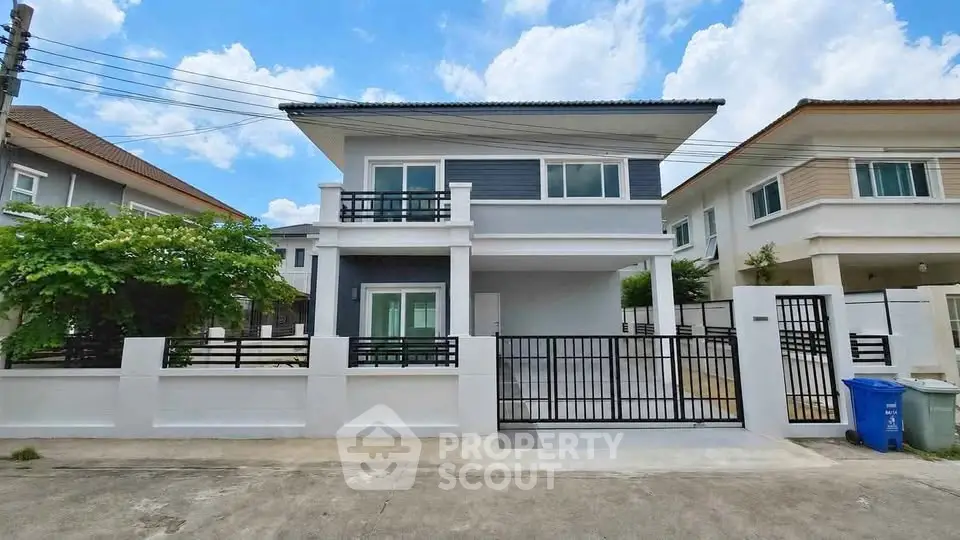 Modern two-story house with sleek design and spacious driveway in a suburban neighborhood.