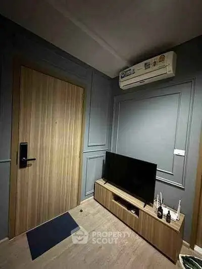 Modern living room with sleek wooden door and stylish TV stand under air conditioning unit.