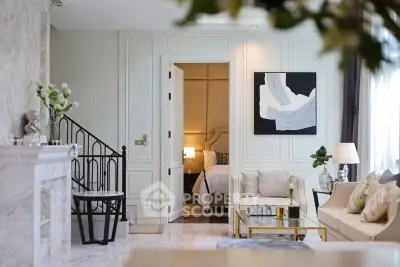 Luxurious living room with elegant decor and view into a cozy bedroom, featuring modern art and stylish furnishings.