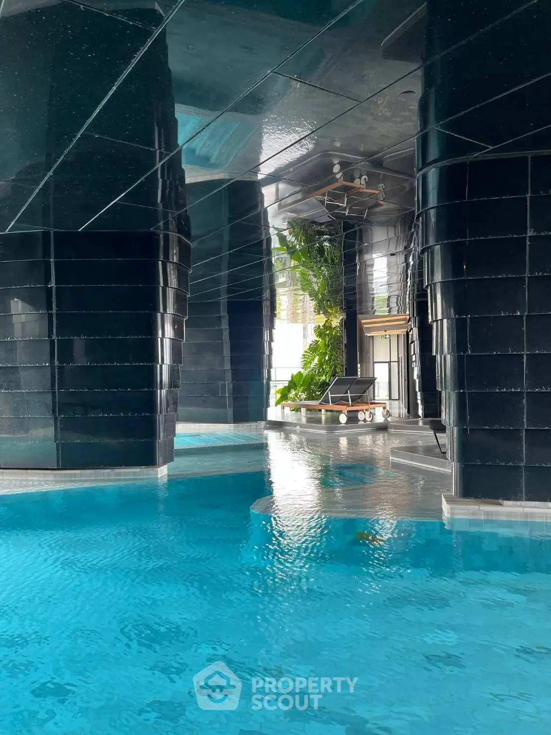 Luxurious indoor pool with modern design and sleek black columns in a high-end residential building.