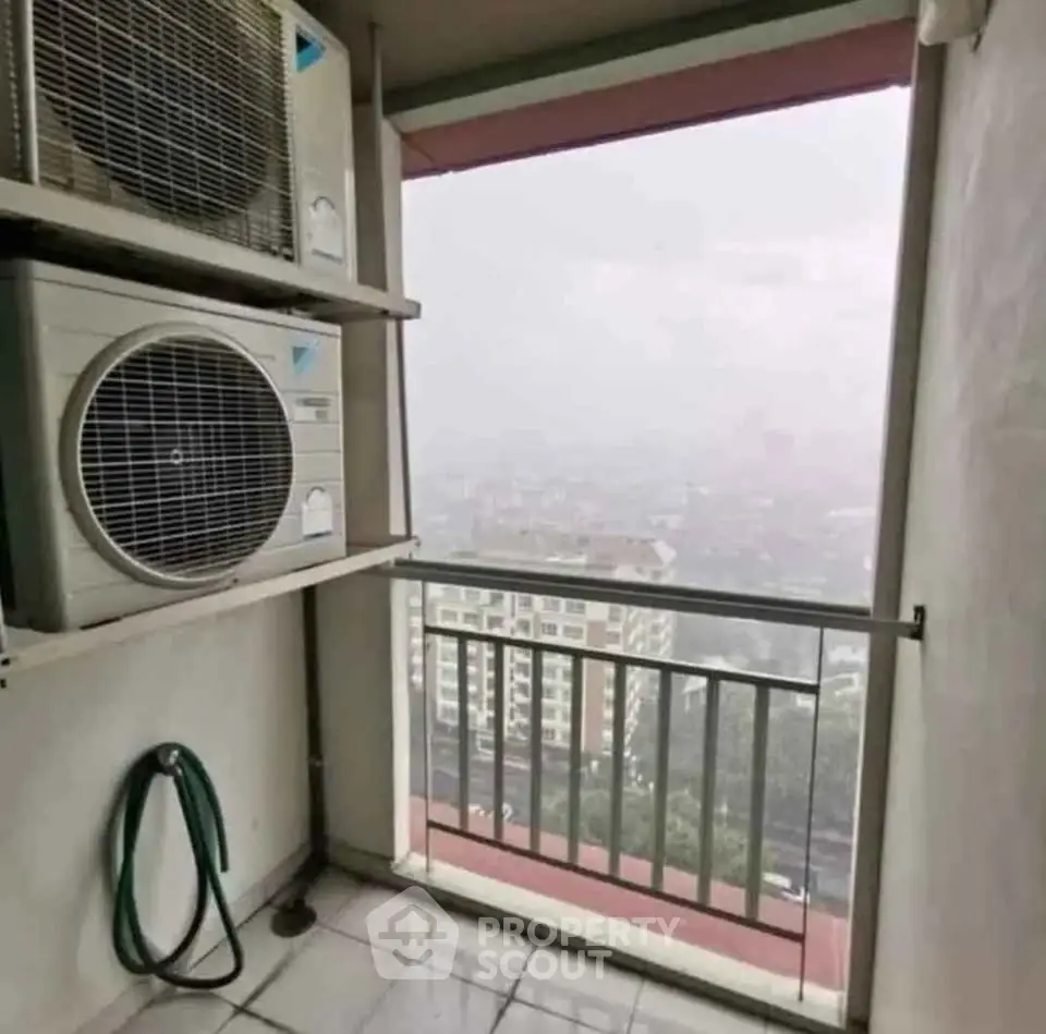 High-rise balcony with air conditioning units and city view on a misty day.