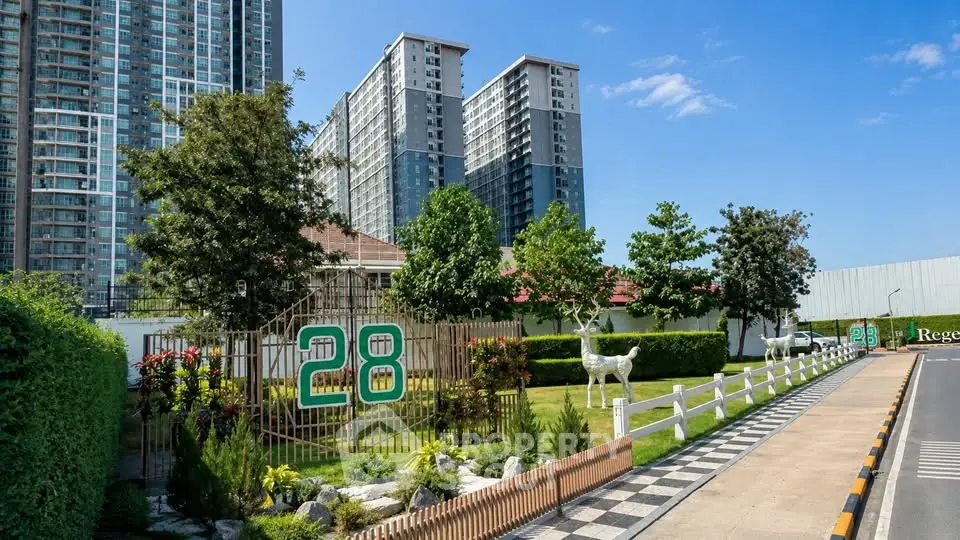 Modern residential complex with lush landscaping and high-rise buildings under a clear blue sky.