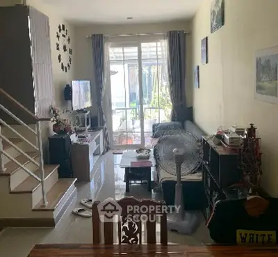 Cozy living room with modern decor and natural light, featuring a staircase and balcony access.