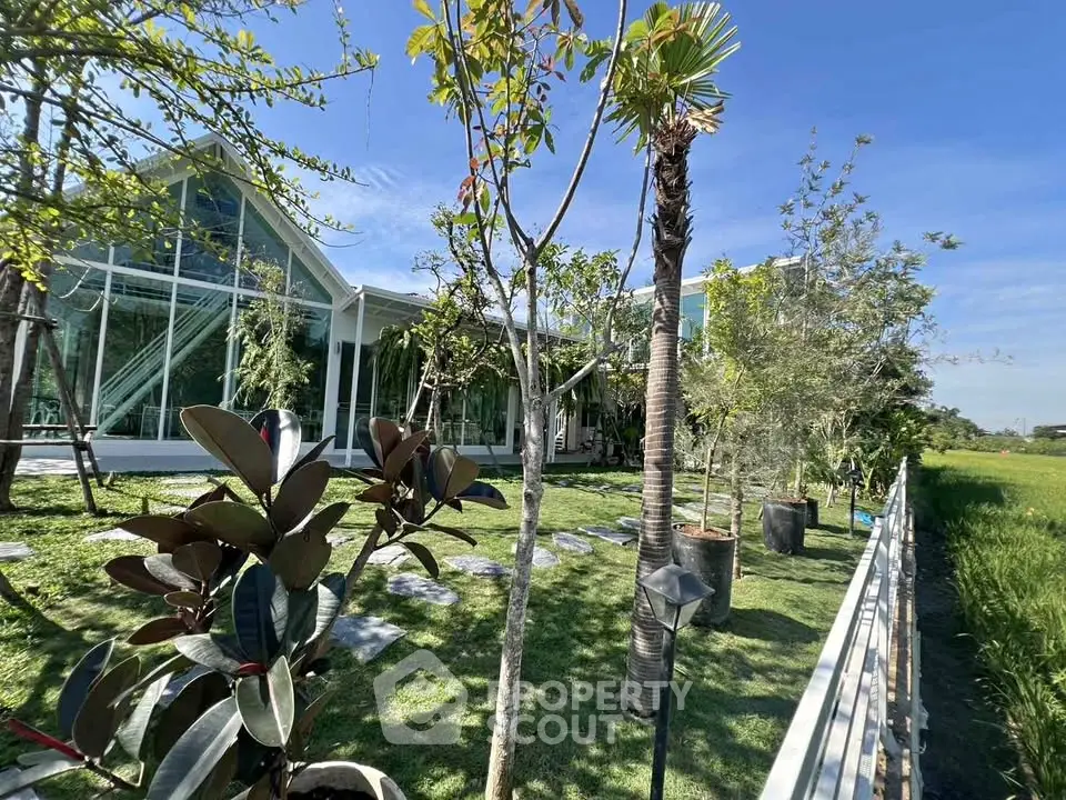 Stunning modern house with lush garden and expansive glass windows, offering serene views and abundant natural light.