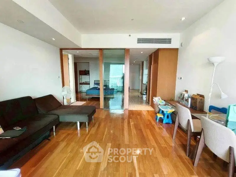 Spacious living room with wooden flooring and modern furniture in a stylish apartment.