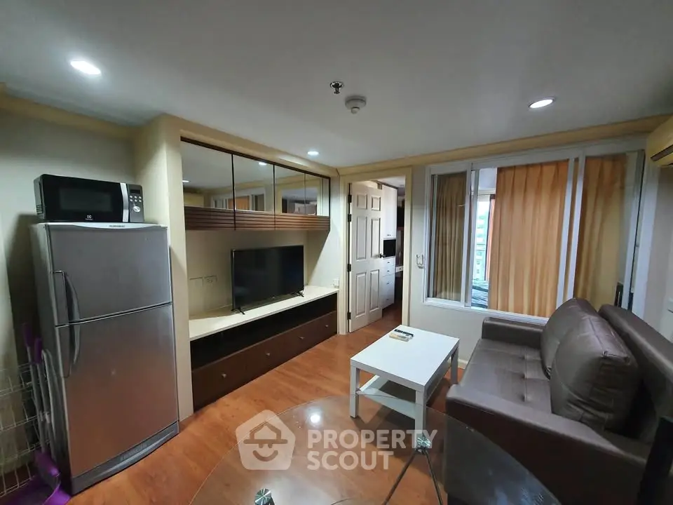 Cozy living room with modern appliances and stylish furniture in a compact apartment setting.