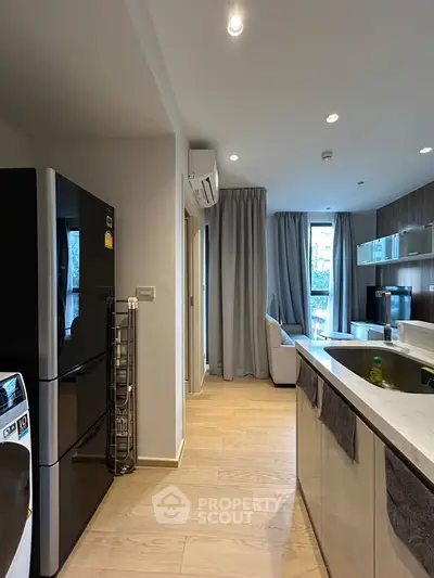 Modern kitchen with sleek appliances and open layout leading to a cozy living area.
