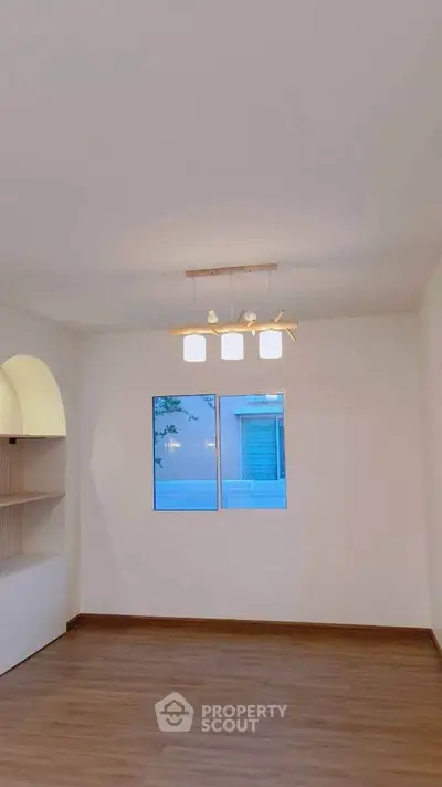Elegant minimalist room with wooden flooring and modern lighting, perfect for versatile living space.