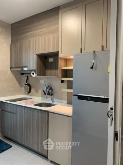 Modern kitchen with sleek cabinetry and stainless steel fridge in compact layout