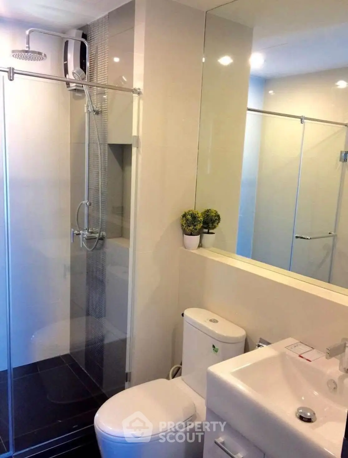 Modern bathroom with glass shower and sleek fixtures in contemporary apartment.