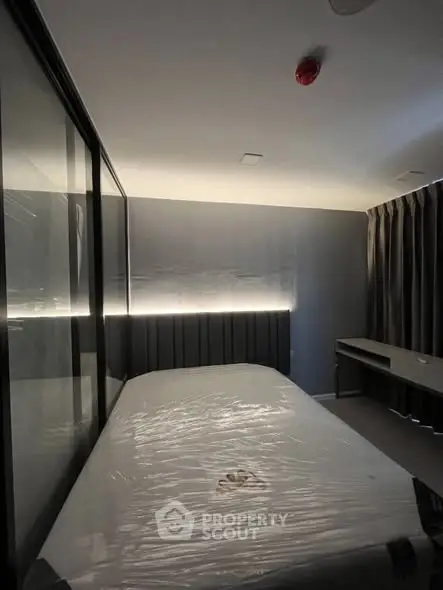 Modern bedroom with sleek design and ambient lighting, featuring a bed and desk setup.