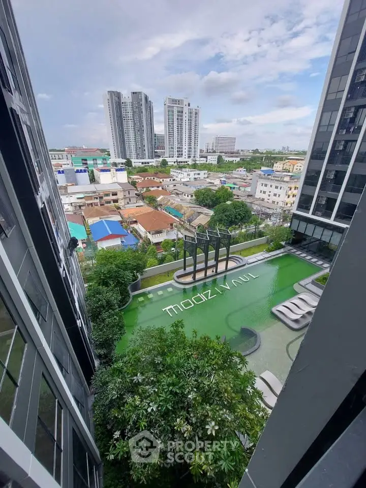 Stunning view of modern apartment complex with pool and cityscape backdrop.