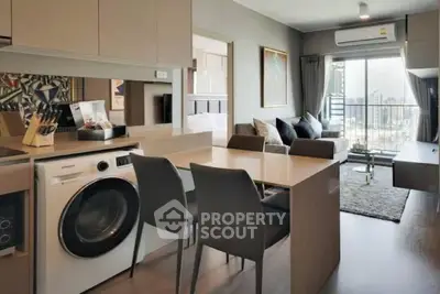 Modern open-plan living room with kitchen and city view, featuring sleek furniture and natural light.