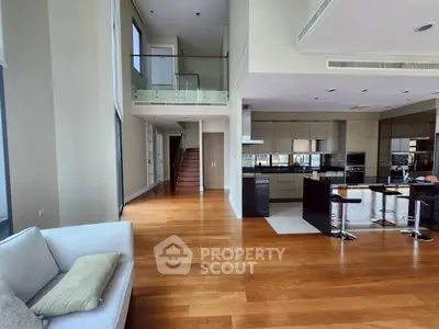 Luxurious open-plan living room with high ceilings and modern kitchen in a spacious apartment.