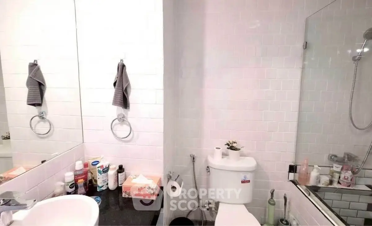 Modern bathroom with sleek fixtures and white tiles, featuring a glass shower enclosure.