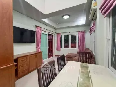 Charming living room with modern decor, featuring a wall-mounted TV, cozy seating, and elegant pink curtains.