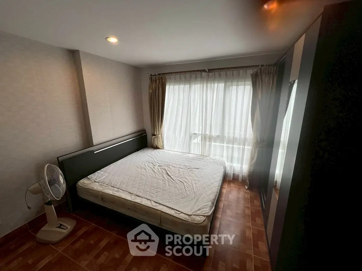 Spacious bedroom with large window and natural light, featuring a comfortable bed and modern decor.