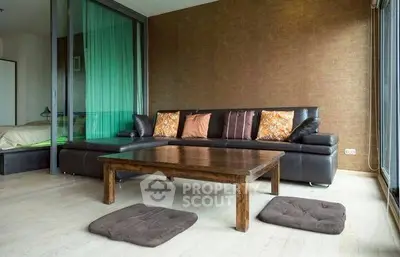 Modern living room with sleek brown sofa and wooden coffee table, featuring floor-to-ceiling windows.