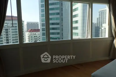 Spacious room with large windows offering stunning cityscape views in a modern high-rise building.