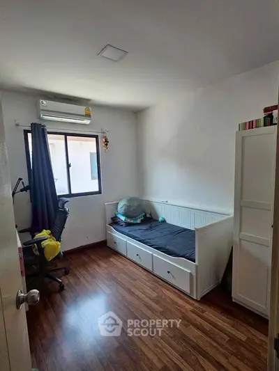 Cozy bedroom with wooden flooring, single bed, and window view, perfect for a peaceful retreat.