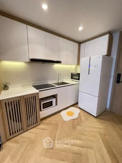Modern kitchen with sleek cabinets, fridge, and microwave in stylish apartment.