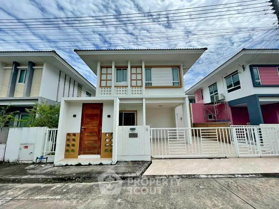 Modern two-story house with stylish facade and gated driveway in suburban neighborhood.