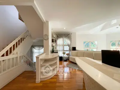 Spacious living room with elegant staircase and natural light