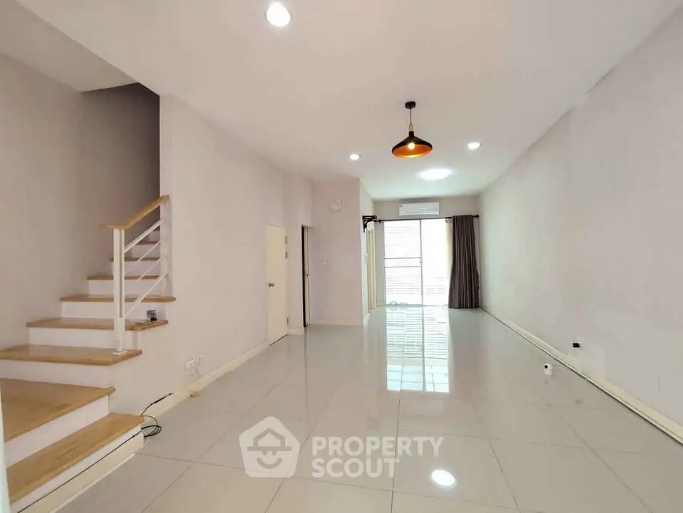 Spacious modern living room with staircase and large windows for natural light.