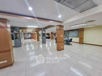 Spacious open-plan office interior with modern lighting and tiled flooring.