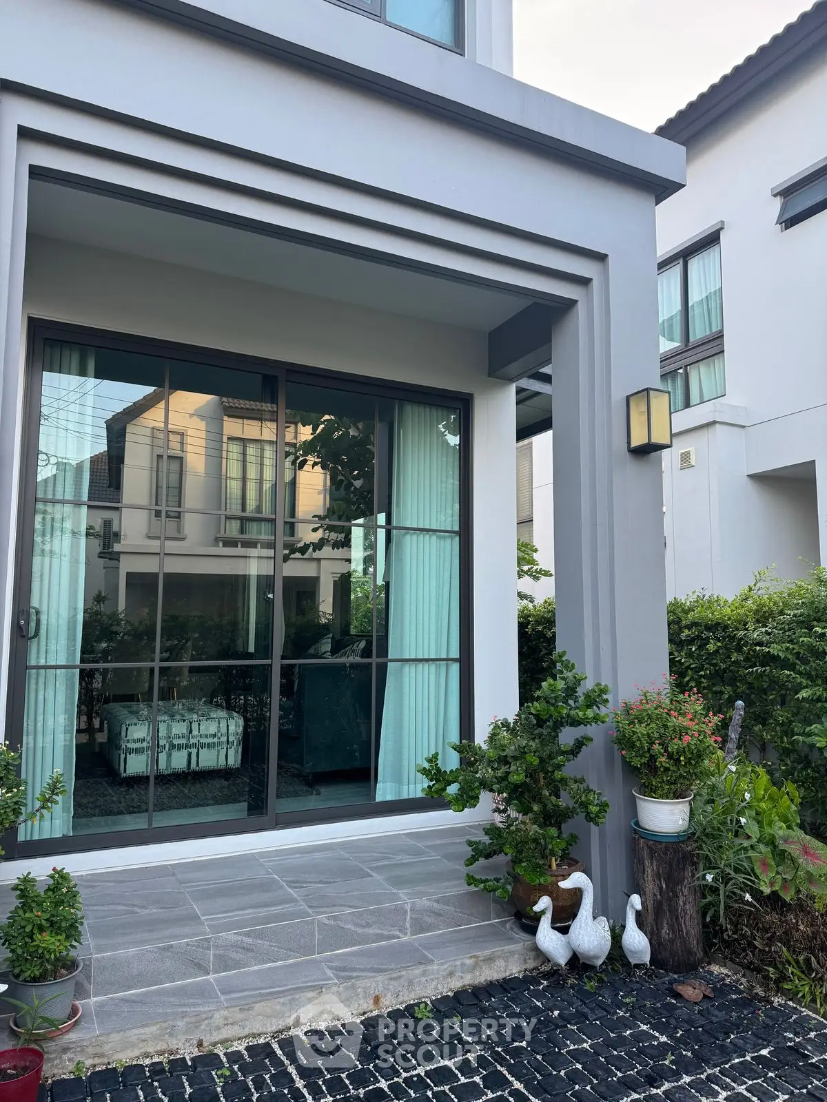 Charming modern home exterior with large windows and lush garden accents.