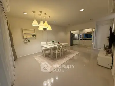 Spacious dining area with modern lighting and sleek kitchen in open layout apartment.