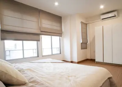 Spacious bedroom with large windows and modern decor in a cozy apartment.