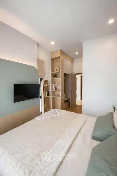 Modern bedroom with stylish decor and built-in storage, featuring a wall-mounted TV and cozy bedding.