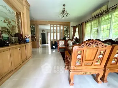 Elegant living room with ornate wooden furniture and large windows offering natural light.