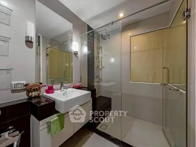 Modern bathroom with glass shower and stylish vanity in contemporary apartment.