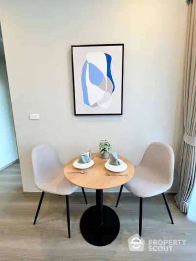 Cozy dining nook with modern chairs and abstract art in stylish apartment.