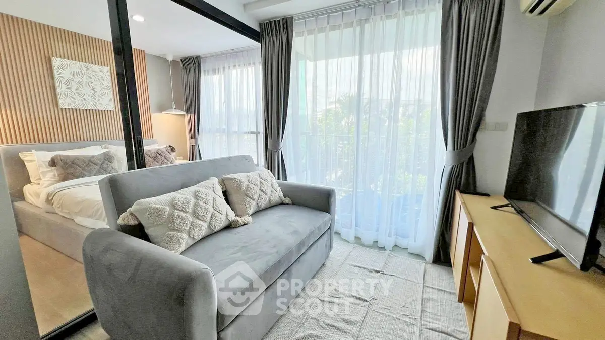 Chic modern living room with cozy sofa, large TV, and floor-to-ceiling windows for natural light.