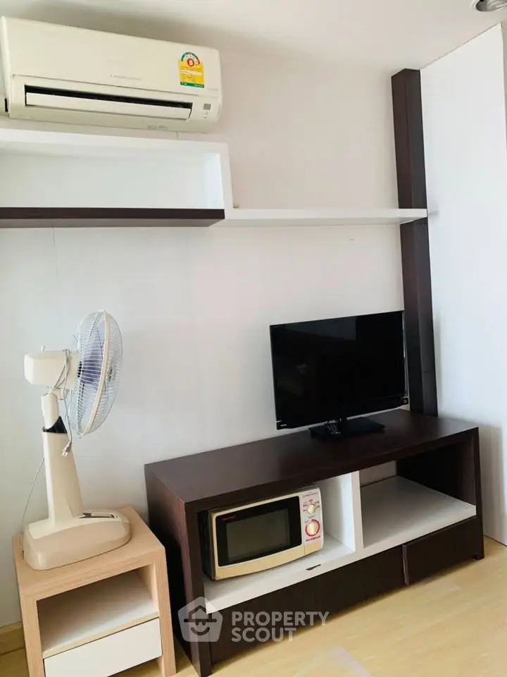 Modern living room with air conditioner, TV, and microwave on stylish furniture.