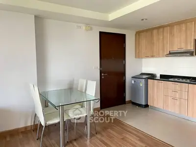 Modern kitchen with dining area featuring glass table and wooden cabinets in a cozy apartment.
