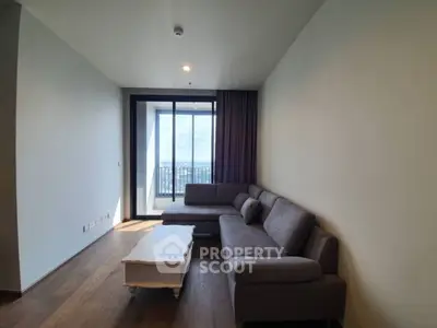 Spacious living room with large windows and balcony access, featuring a modern sectional sofa.