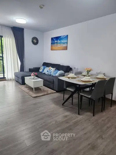Spacious living room with modern decor and dining area, featuring a cozy sofa and elegant table setting.