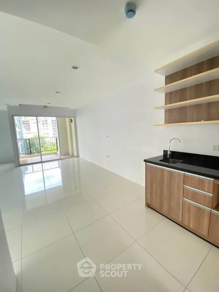 Spacious open-plan living area with modern kitchen and balcony view.