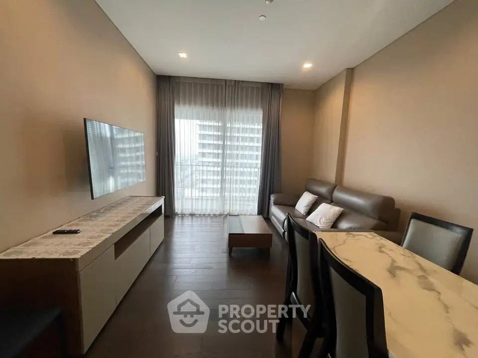 Modern living room with sleek furniture and large window offering natural light.