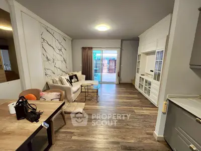 Spacious living room with modern decor and large windows opening to a balcony.