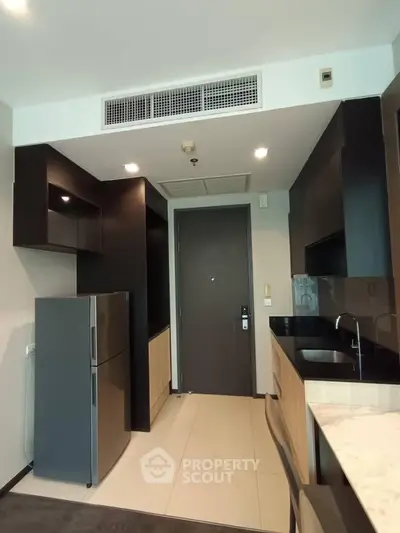 Modern kitchen with sleek black cabinetry and stainless steel appliances in a contemporary apartment.