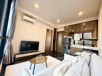 Modern living room with open kitchen, sleek furniture, and natural light.