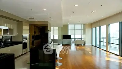 Spacious modern living room with open kitchen and large windows offering city views.