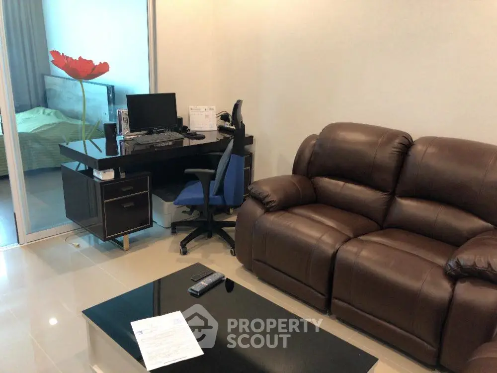 Modern living room with leather sofa and home office setup, ideal for work-from-home lifestyle.