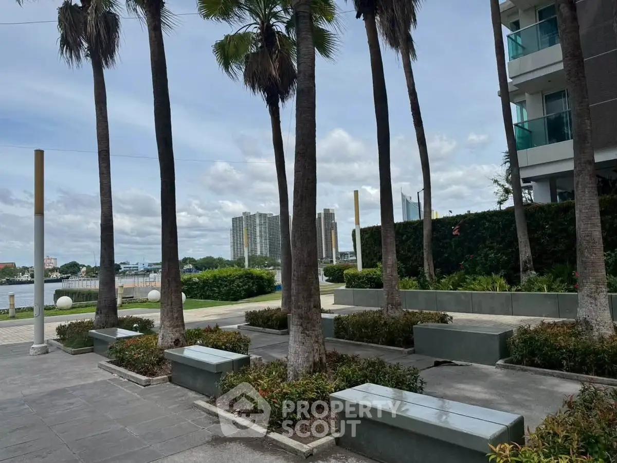 Scenic view of modern waterfront apartment with lush landscaping and palm trees.